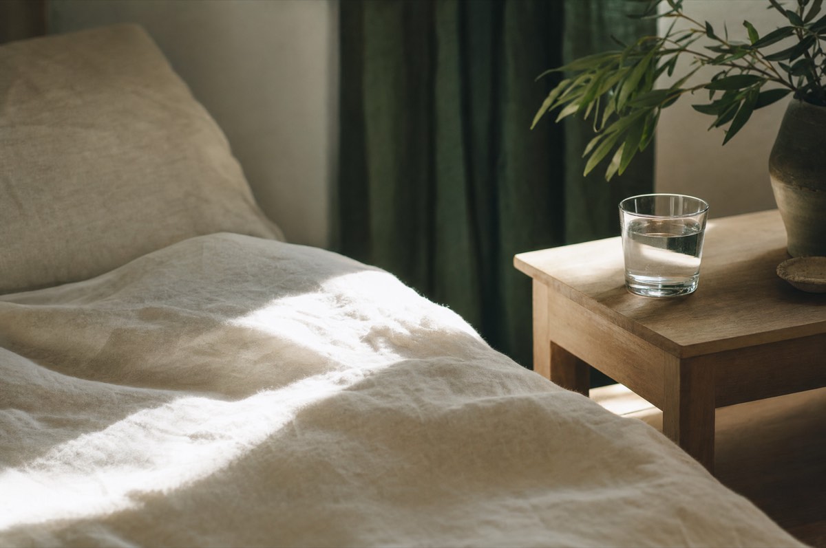 Morning light falling across a linen bedspread and a bedside table